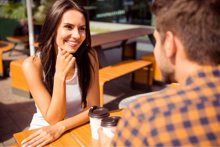 un homme et une femme souriants sont assis à une table et parlent