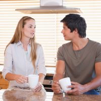 un homme et une femme dans la cuisine sont assis en train de boire du café et de parler