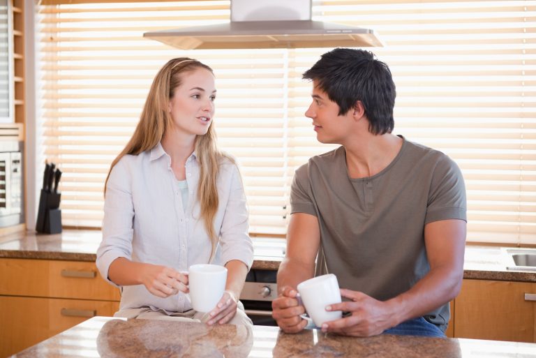un homme et une femme dans la cuisine sont assis en train de boire du café et de parler