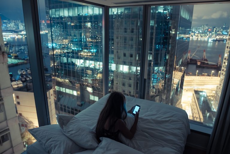 femme assise dans son lit et clé sur le téléphone