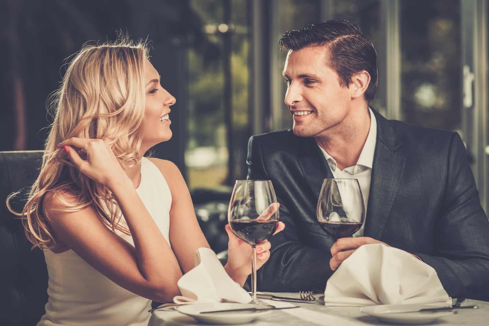 Cheerful couple dans un restaurant avec des verres de vin rouge