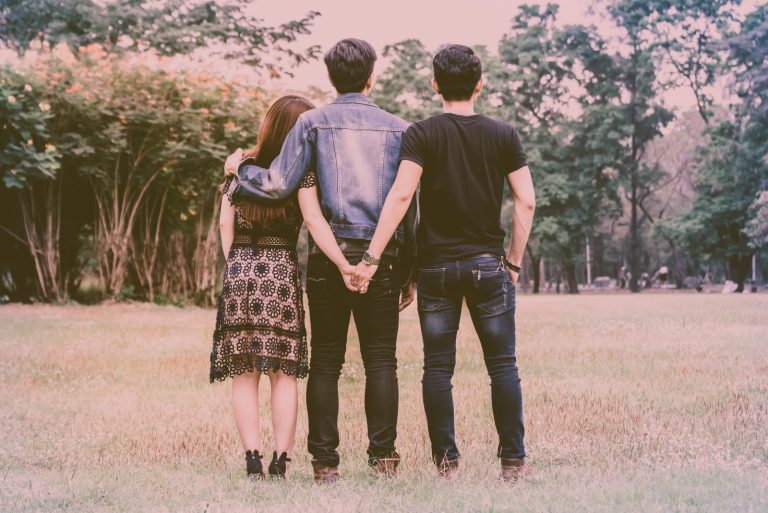 deux hommes et une femme s'embrassent sur le terrain, le dos tourné