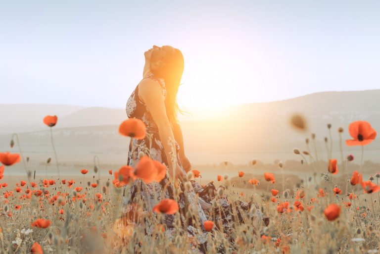 belle fille dans un champ de coquelicots au coucher du soleil