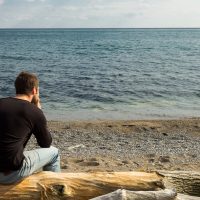un homme est assis et regarde la mer