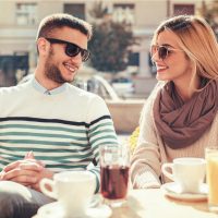 un homme et une femme rient en buvant du café en plein air