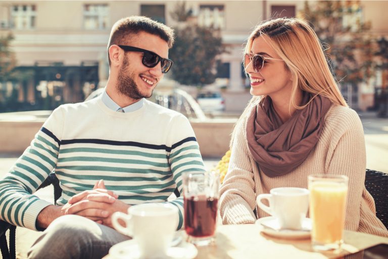 un homme et une femme rient en buvant du café en plein air