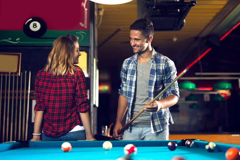 un homme et une femme flirter en se tenant debout près de la table de billard