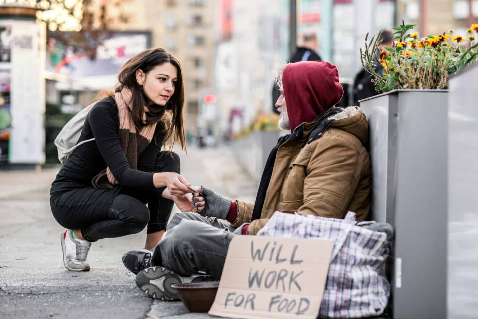 Jeune femme donnant de l'argent à l'homme mendiant sans-abri