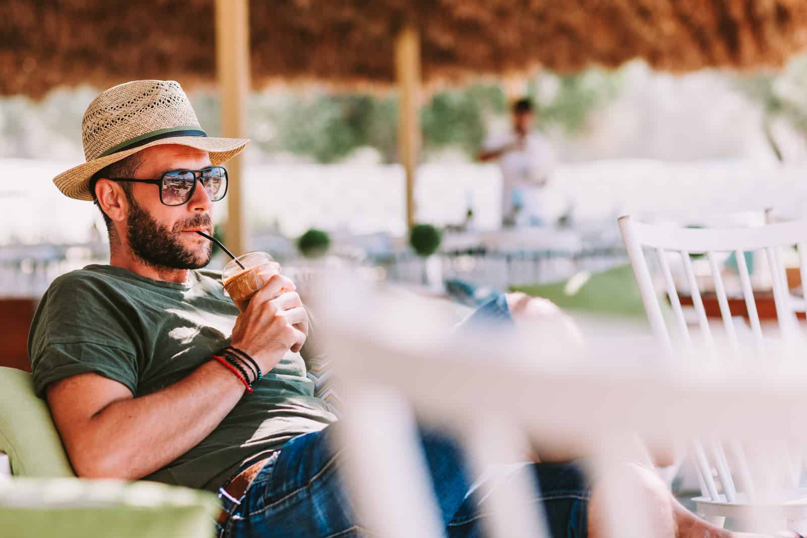 Jeune homme buvant du café glacé dans un bar de plage