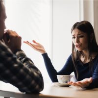 un homme et une femme s'assoient à une table et se disputent