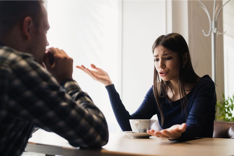 un homme et une femme s'assoient à une table et se disputent