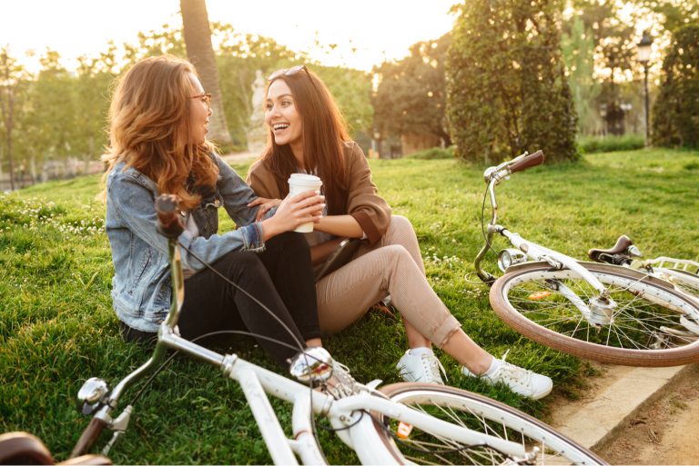 deux amis souriants assis sur l'herbe et riant