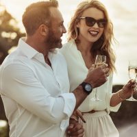 un couple souriant amoureux debout tout en tenant des verres à vin