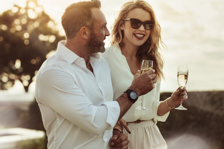 un couple souriant amoureux debout tout en tenant des verres à vin