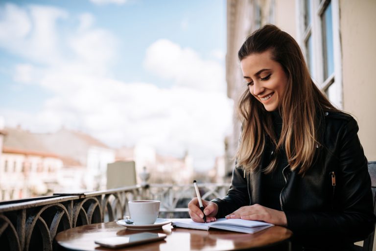 une femme souriante est assise à écrire une lettre