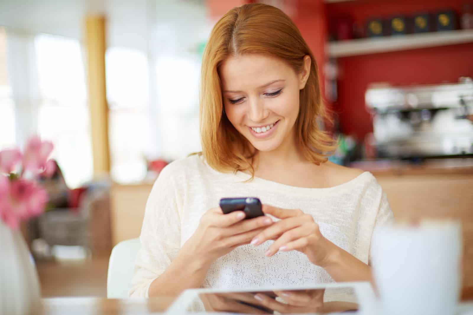 jeune femme lisant des sms au téléphone au café