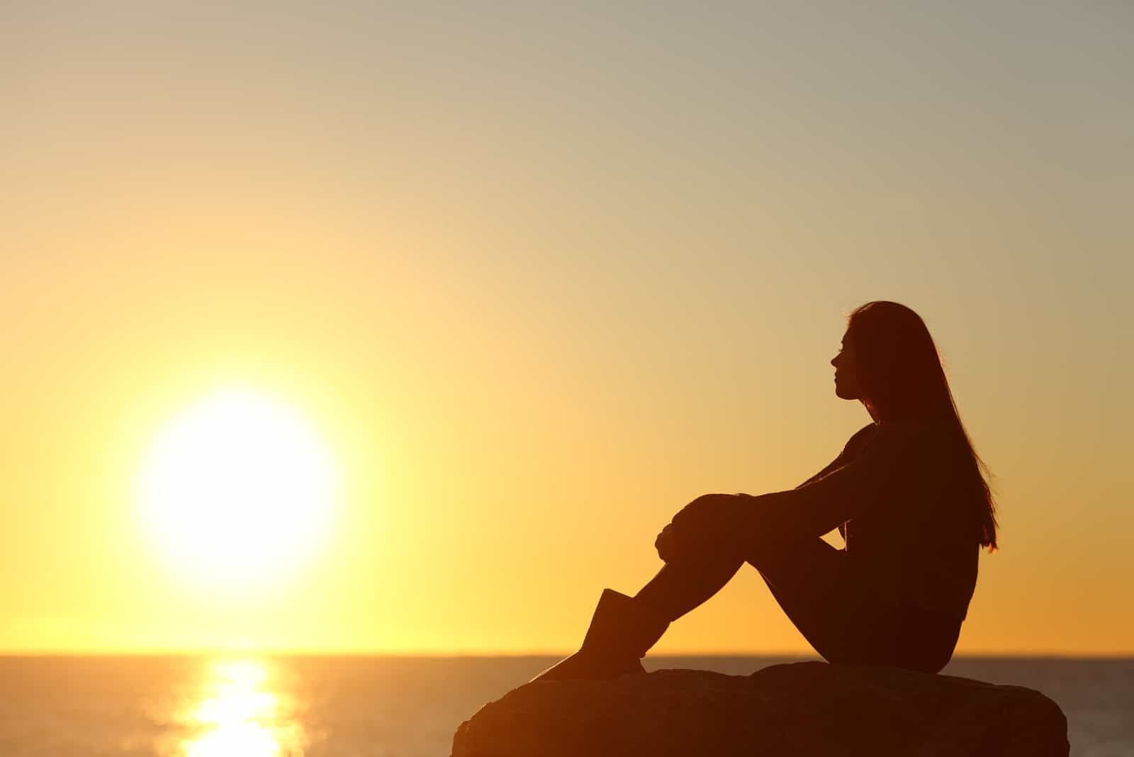 silhouette de femme regardant le soleil sur la plage au coucher du soleil