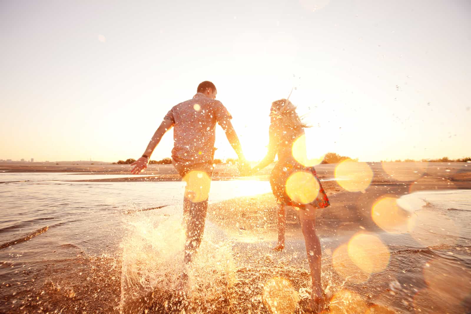 un couple amoureux heureux se tenant la main et courant le long de la plage