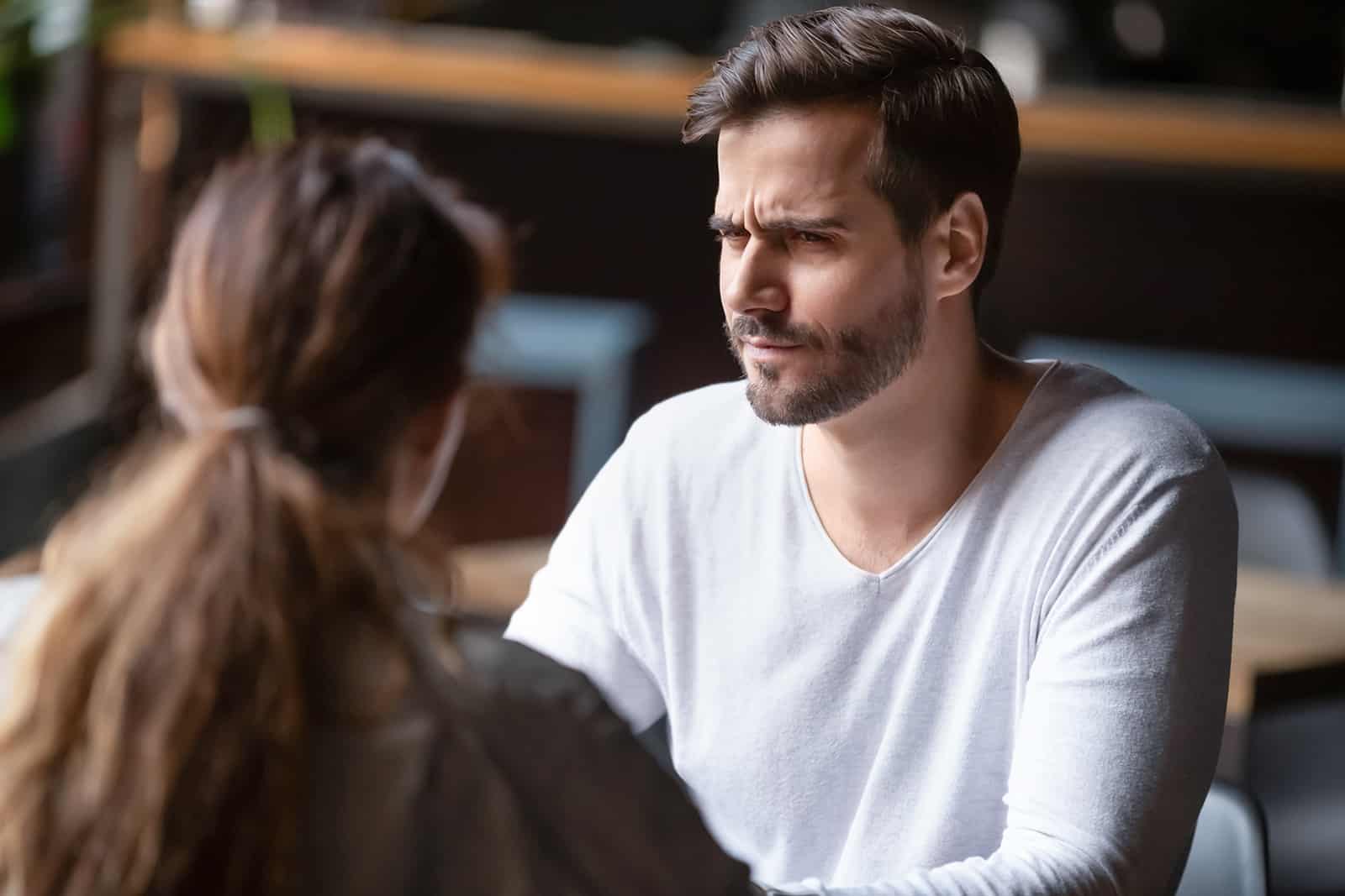 Un homme confus regardant une femme alors qu'il était assis ensemble dans un café