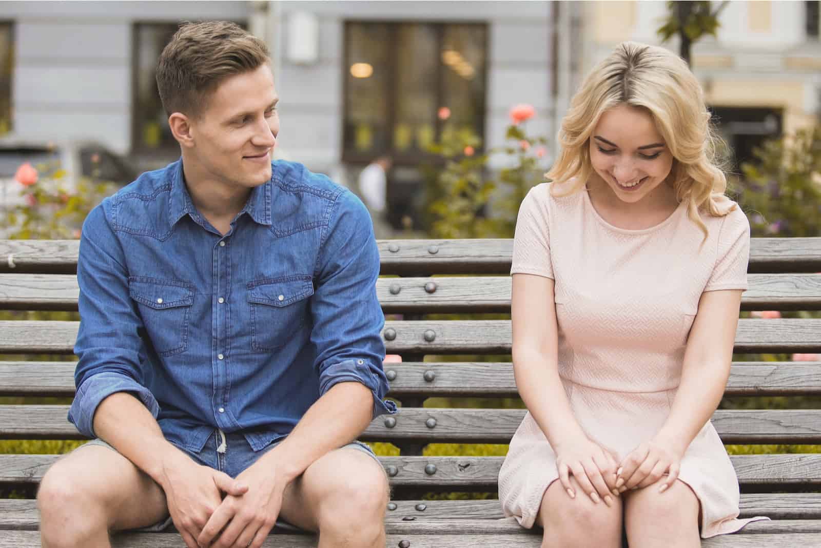 un homme est assis sur un banc et parle à une femme timide