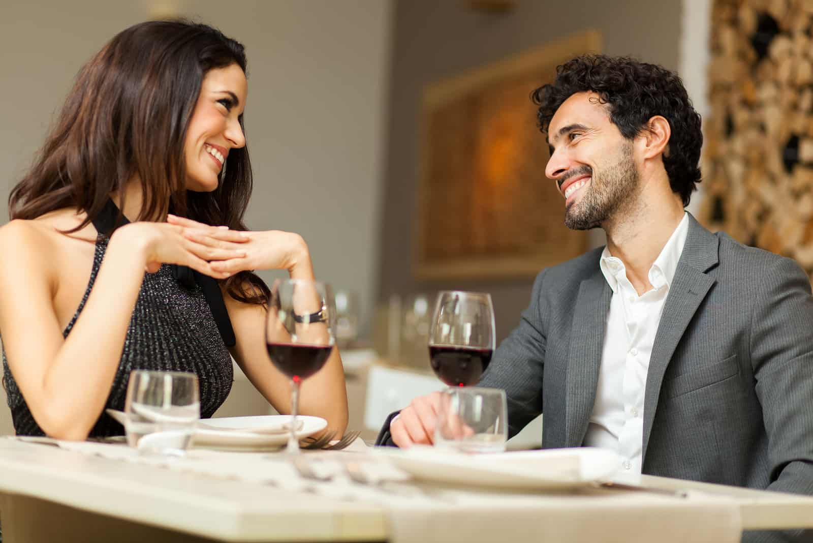 un homme et une femme assis à une table buvant du vin