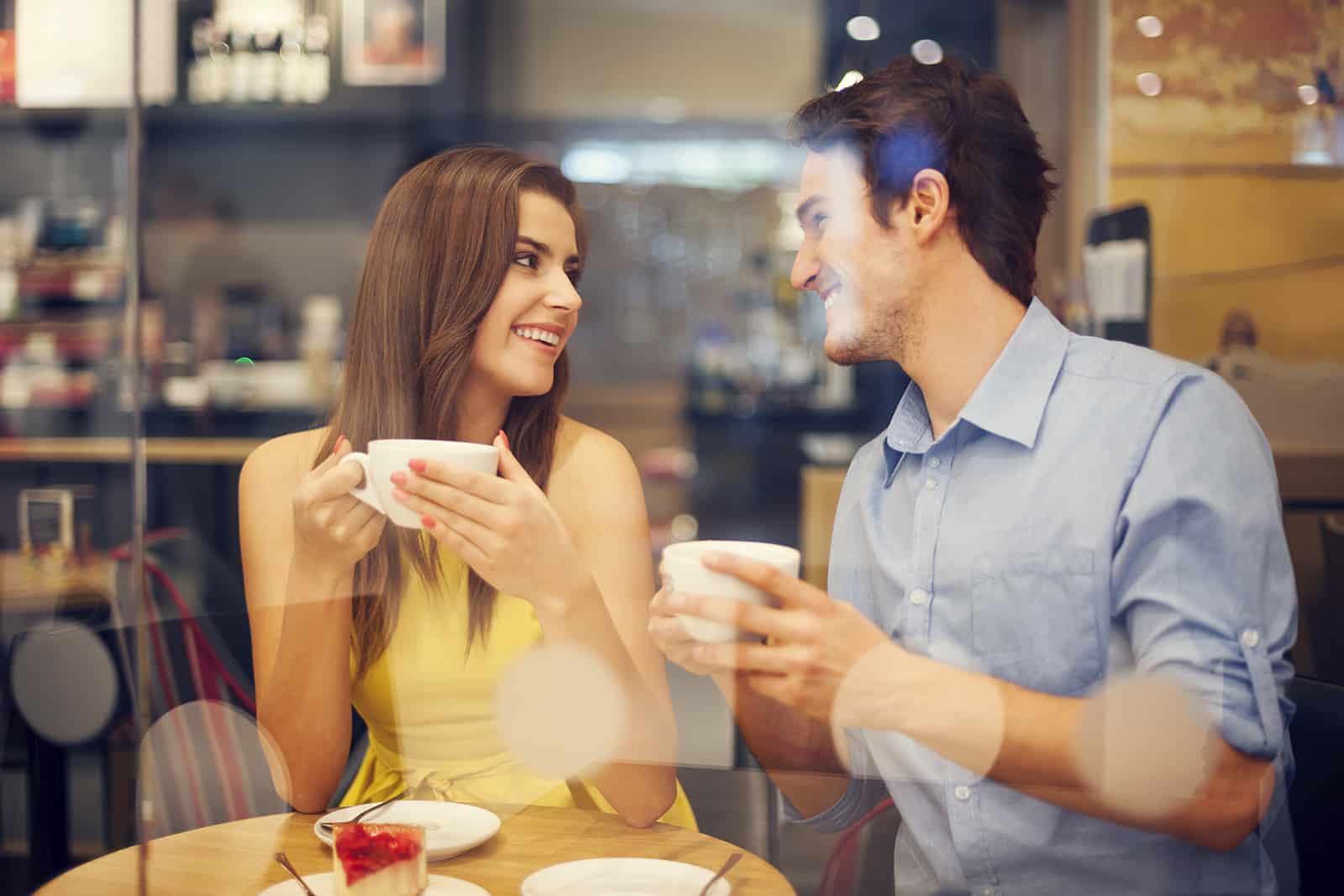 un homme et une femme riant dans le café et se regardant