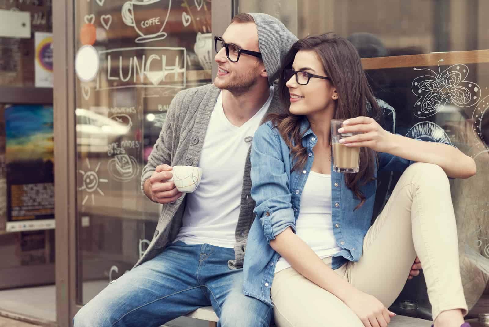 un homme et une femme s'asseoir en buvant du café et en détournant les yeux