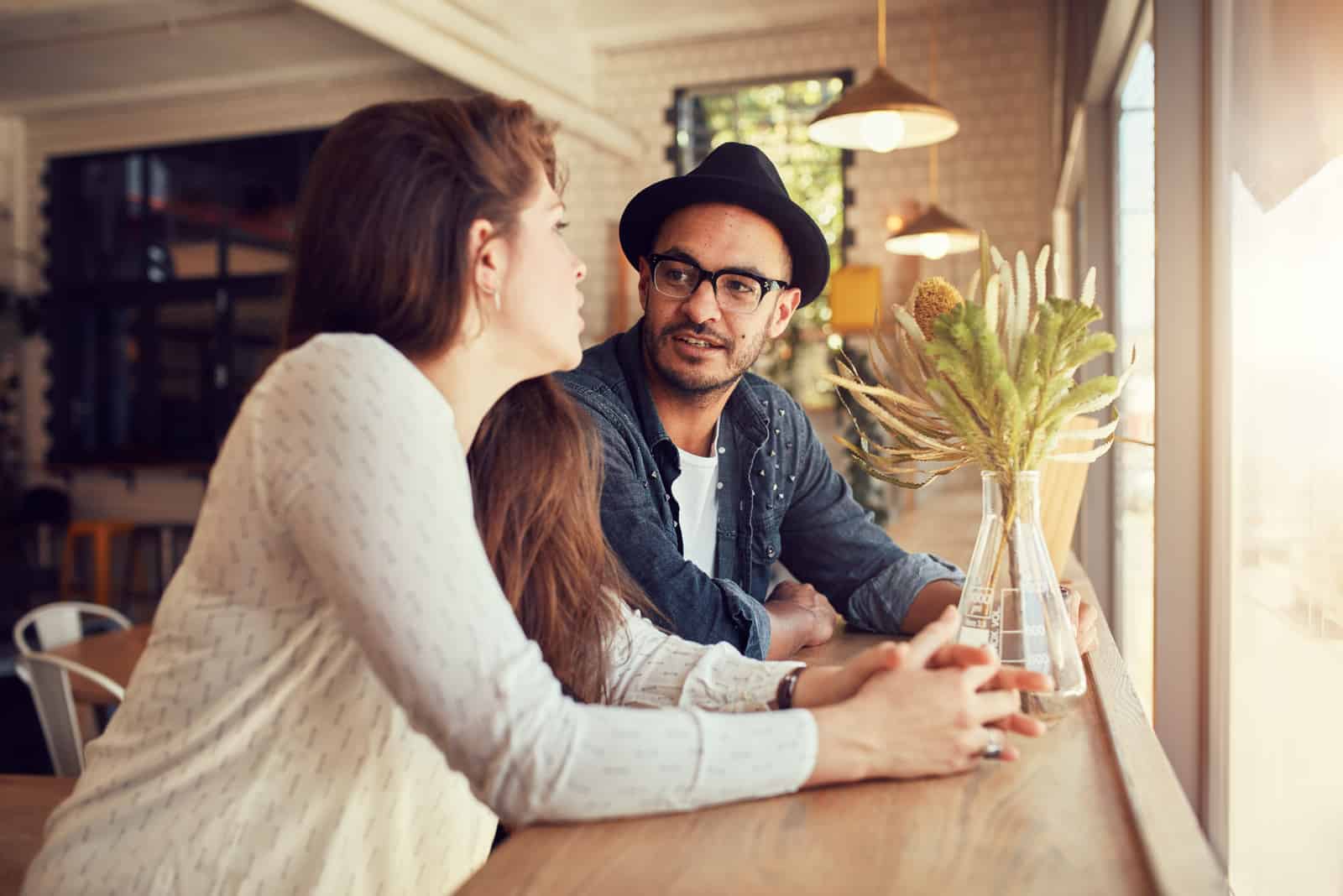 un homme et une femme s'assoient dans un café et parlent