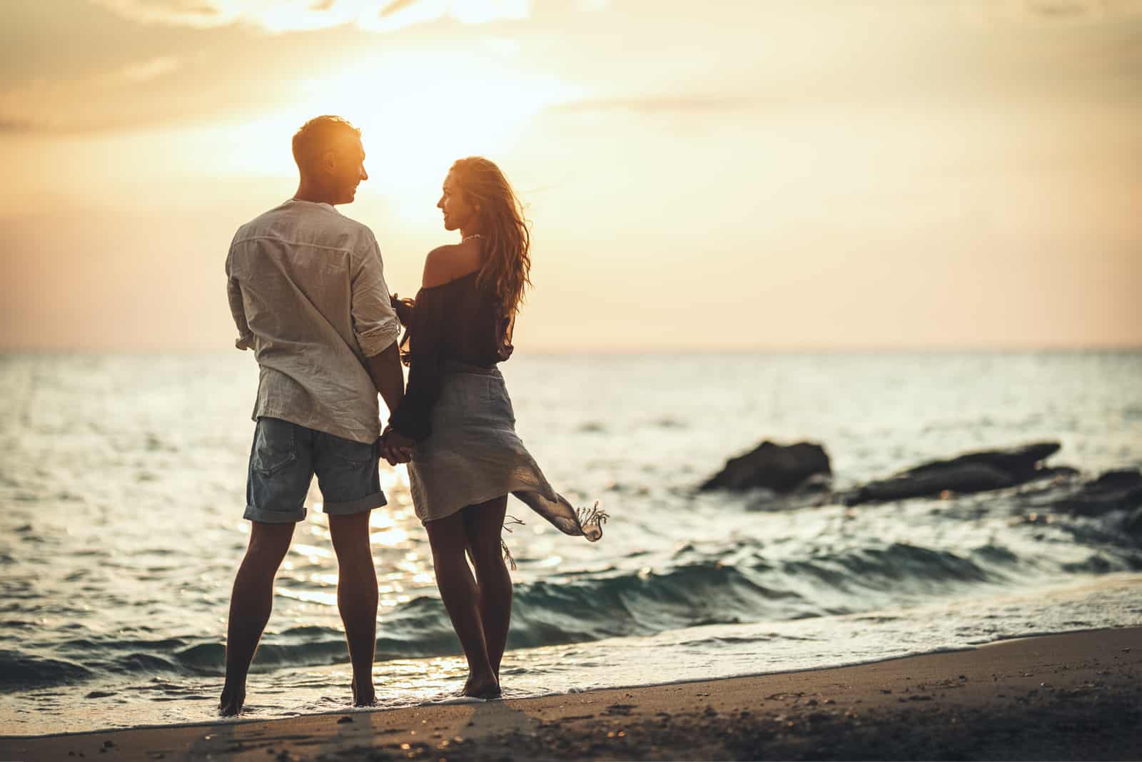 un homme et une femme se tenant la main au bord de la plage