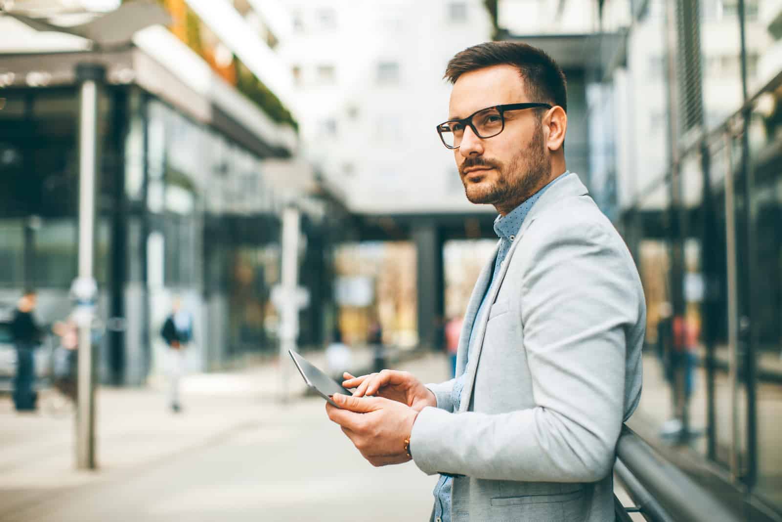 un homme se tient avec des lunettes tout en tenant un téléphone dans sa main