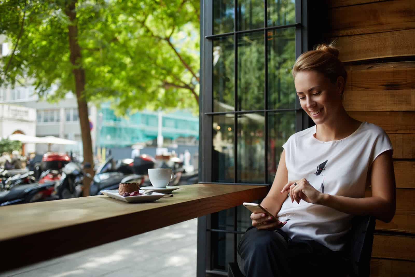 une femme assise dans un café et en appuyant sur un téléphone