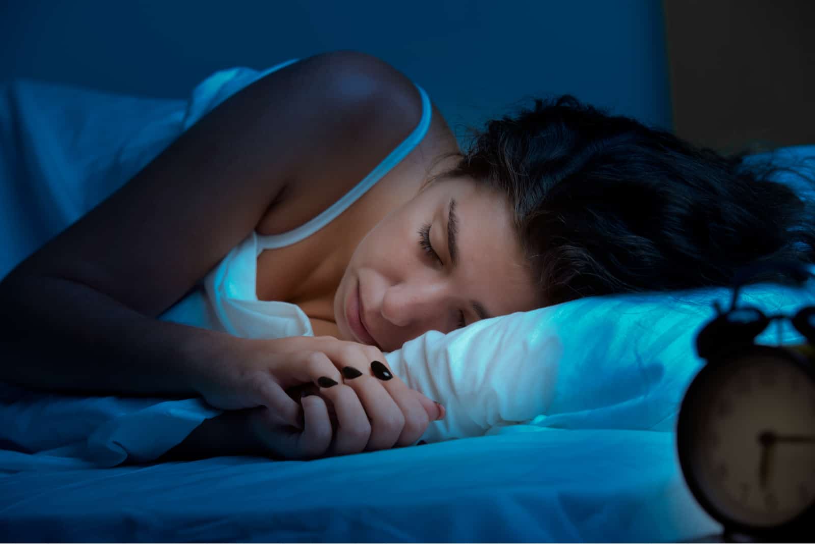 une femme aux longs cheveux noirs dort dans son lit