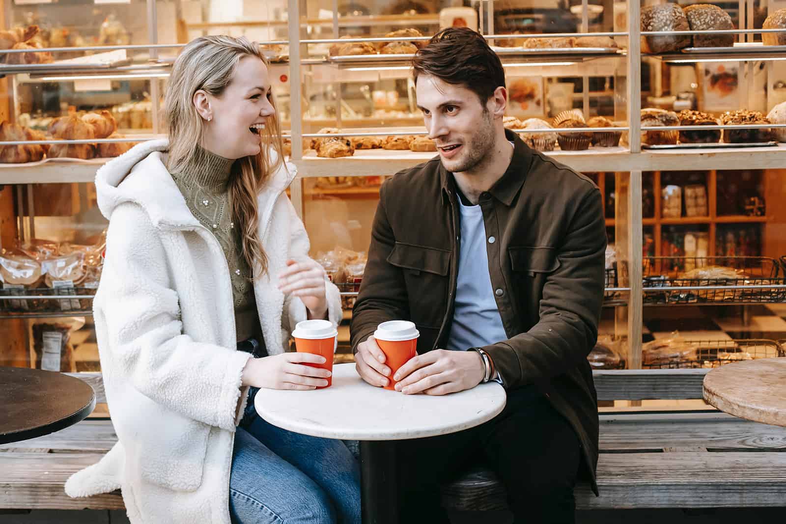 Une femme en riant parlant avec un petit ami à un rendez-vous dans une boulangerie
