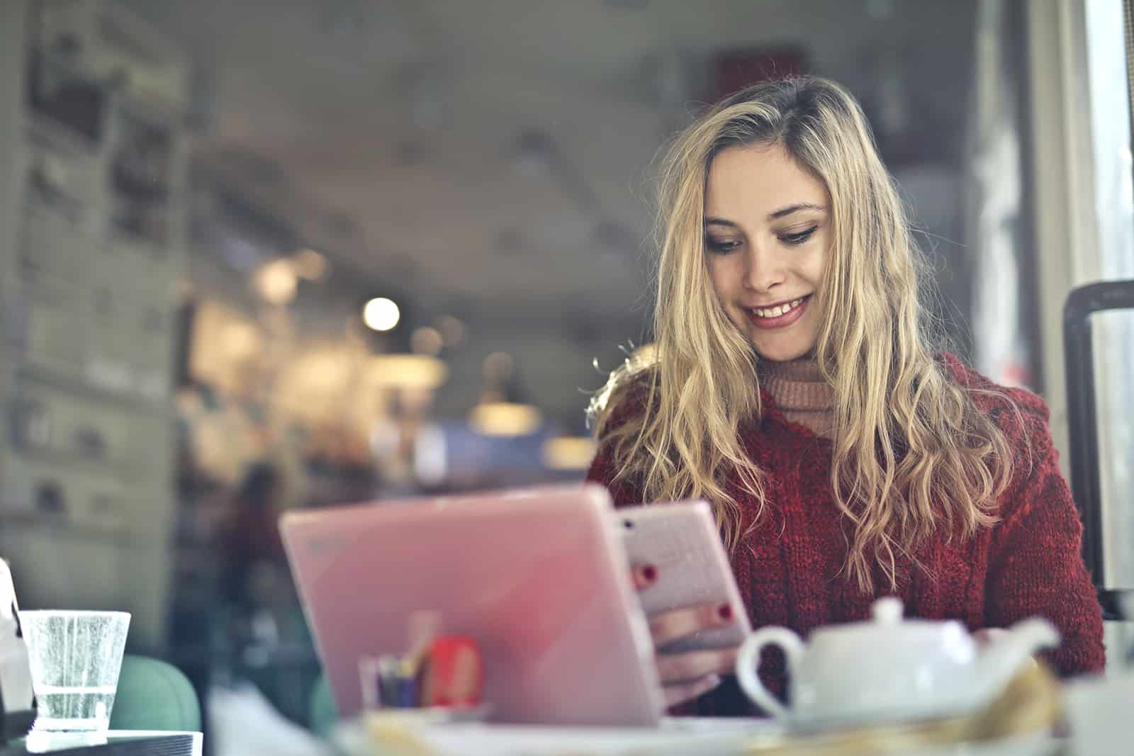 Une femme souriante lisant un message sur le smartphone alors qu'il était assis dans un café