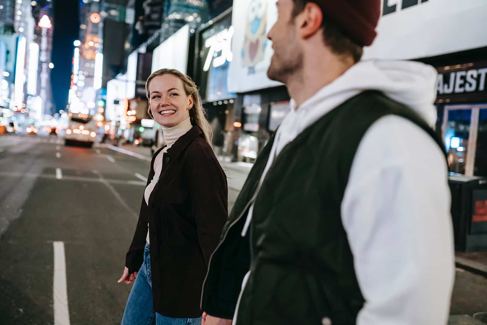 Une femme souriante regardant un homme tout en traversant une rue ensemble