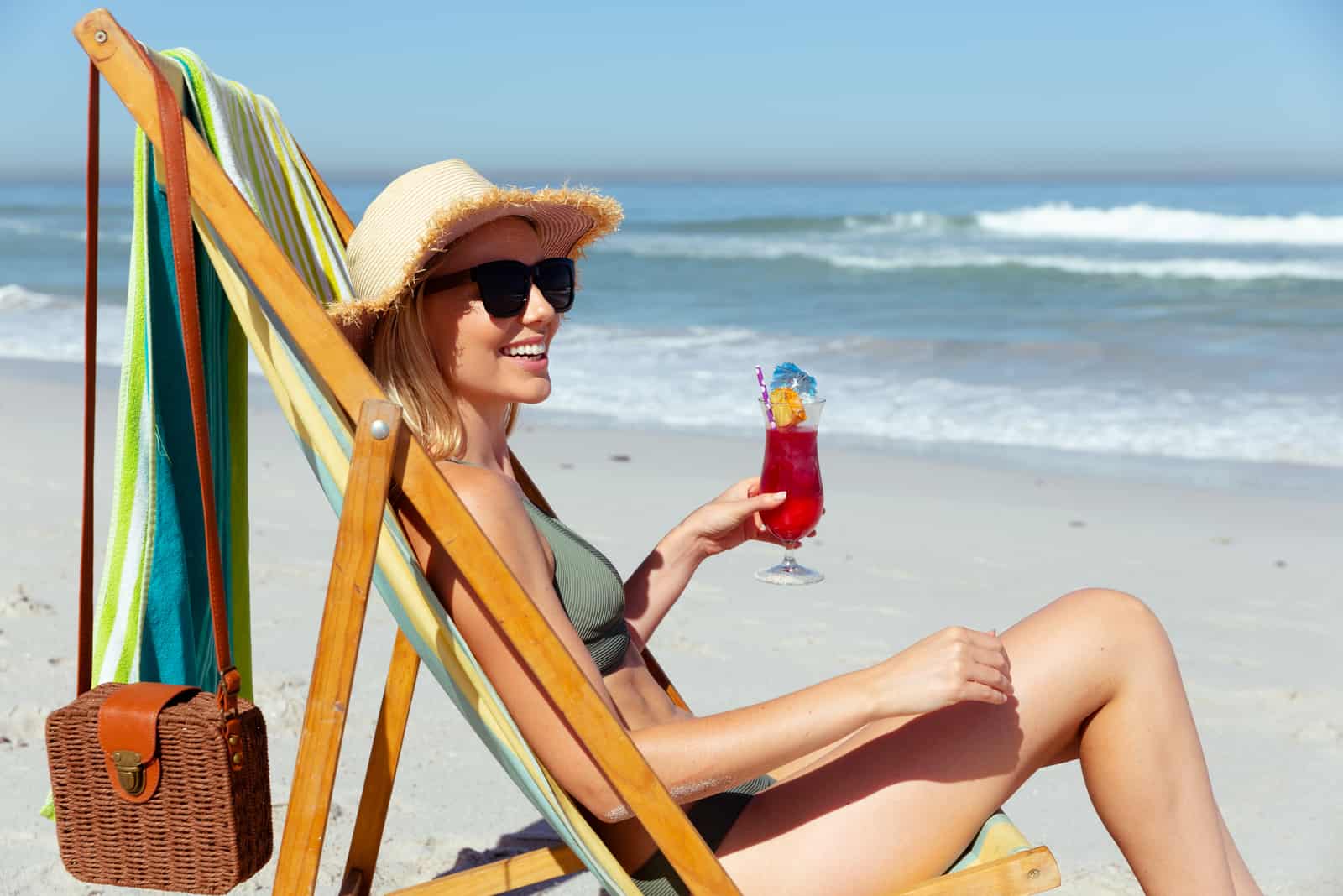 une femme souriante se trouve sur la plage et les bains de soleil