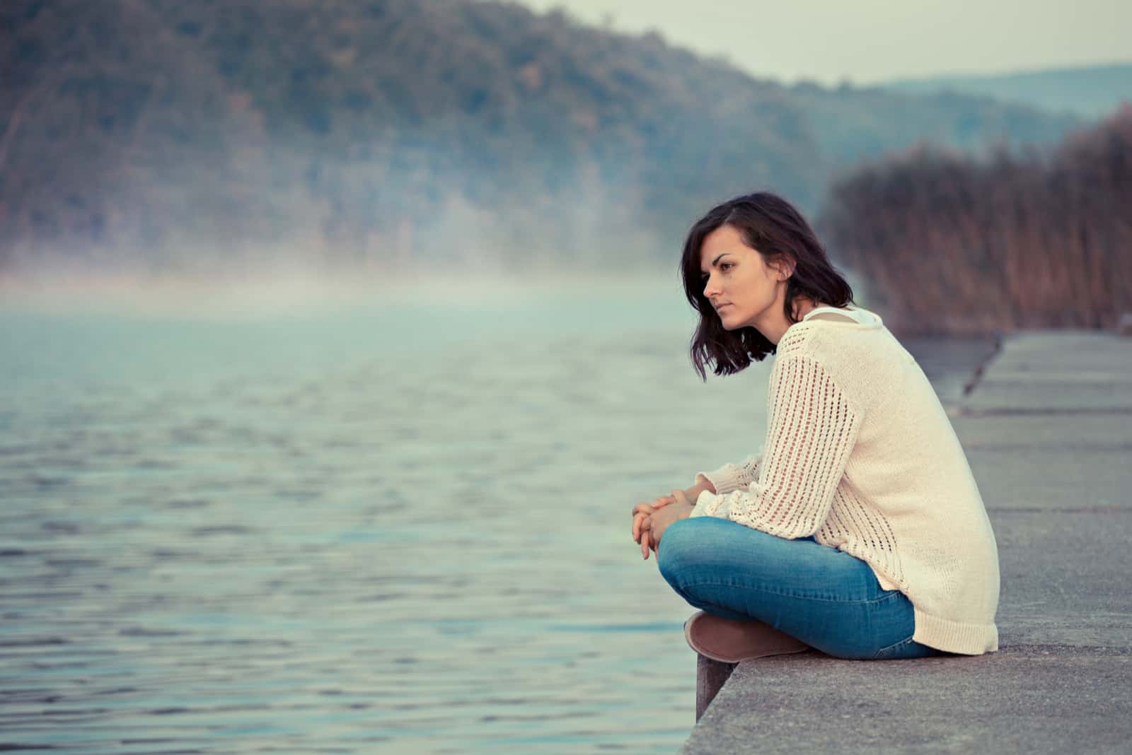 une femme triste assise sur la jetée