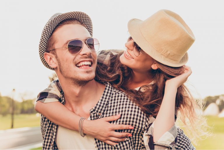 un homme souriant porte une femme pendant qu'elle le regarde et sourit