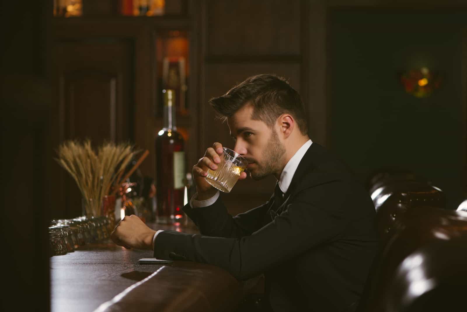 Bel homme vêtu d'un smoking noir dans un bar à whisky