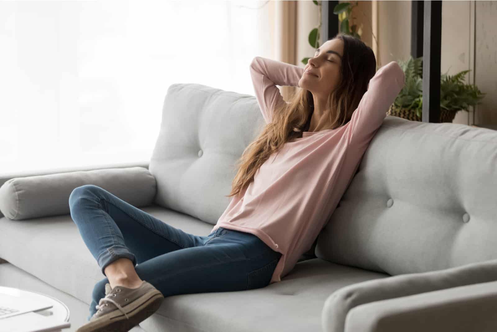Femme assez reposante sur le canapé dans le salon
