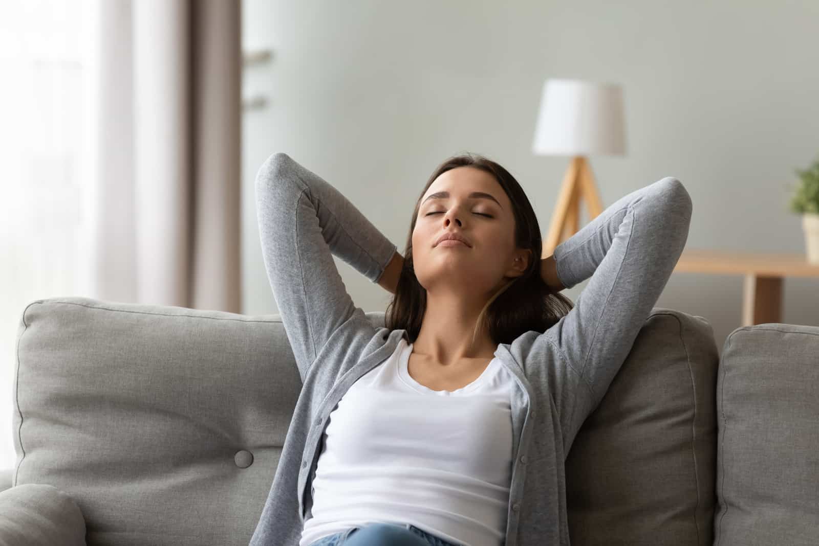 Femme au repos assis sur un canapé dans un salon chaleureux et lumineux