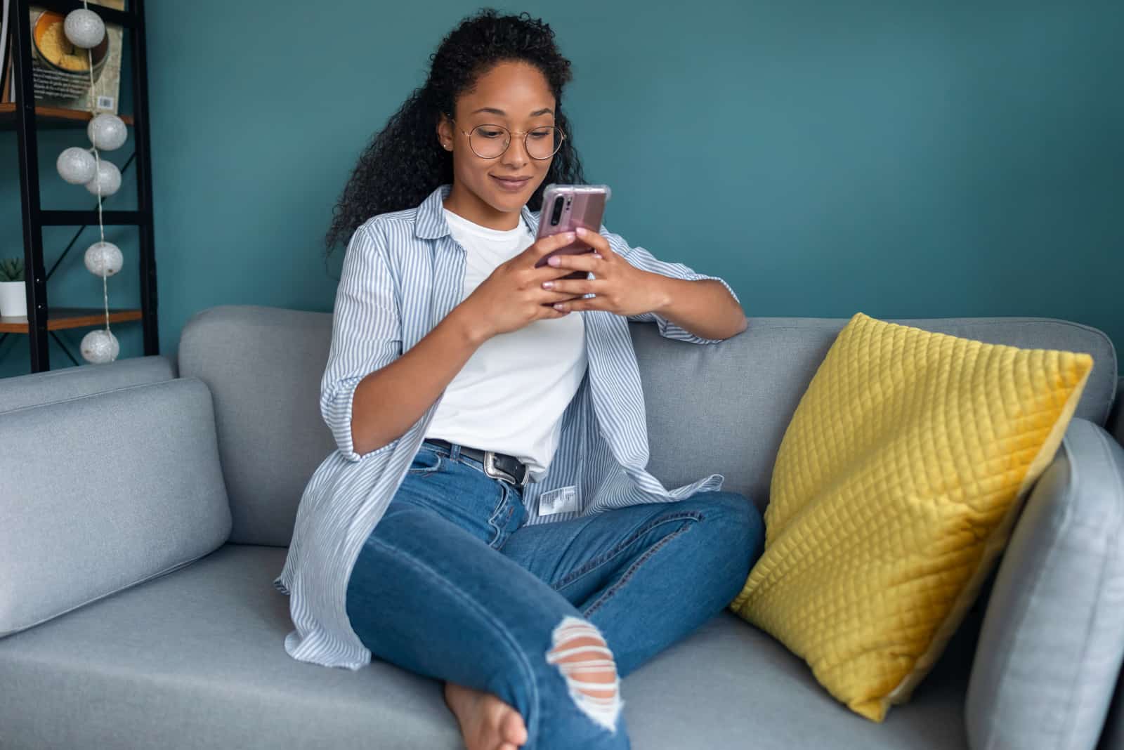Femme à l'aide de son téléphone portable assis sur un canapé à la maison