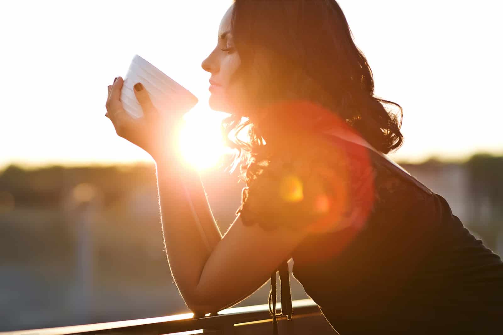 Femme buvant du café en plein air dans la lumière du soleil