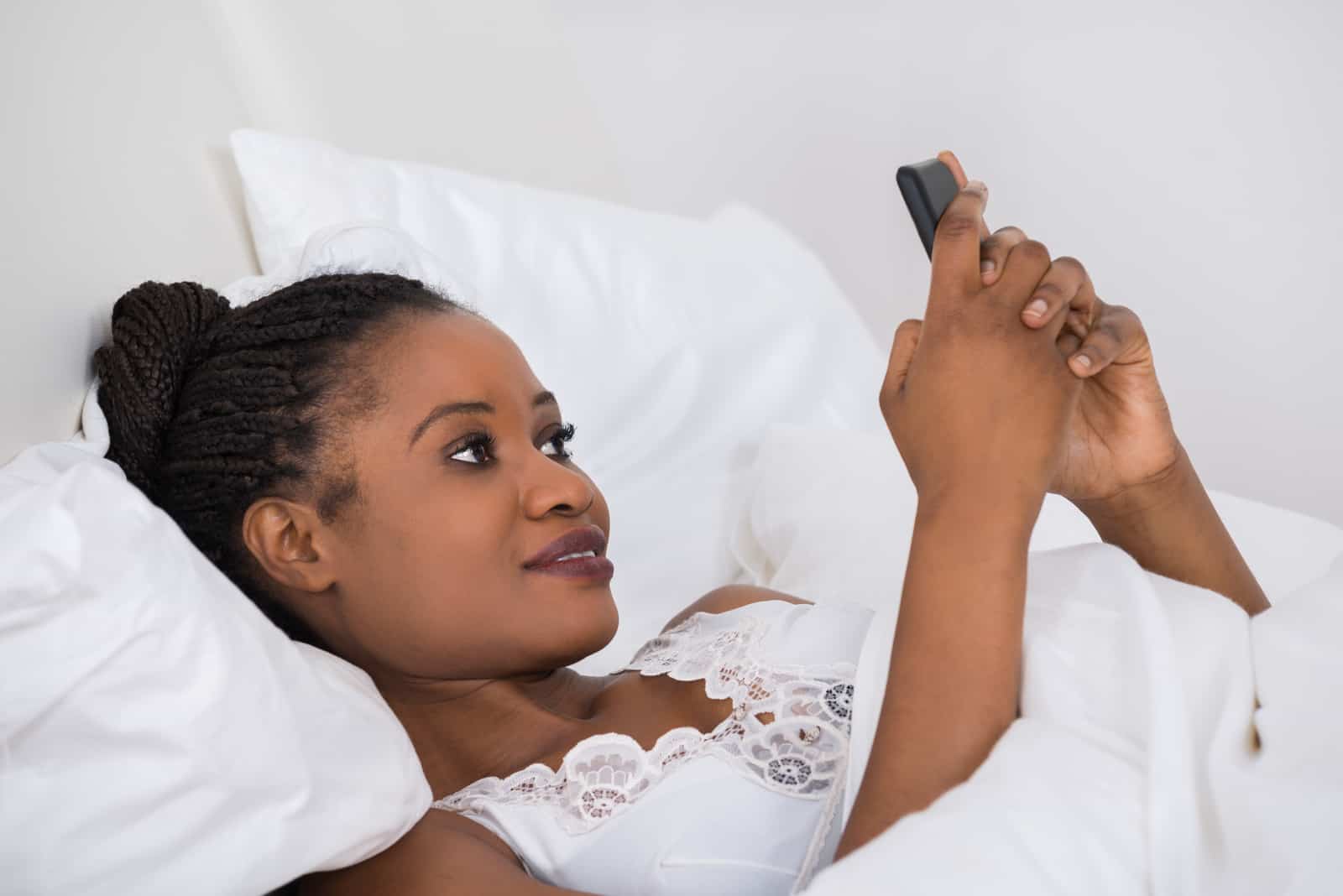Femme coucher lit utilisation téléphone portable