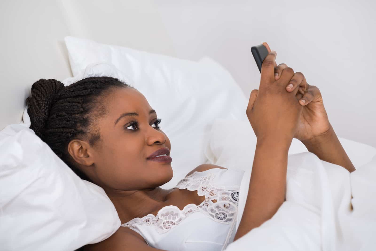 Femme coucher lit utilisation téléphone portable