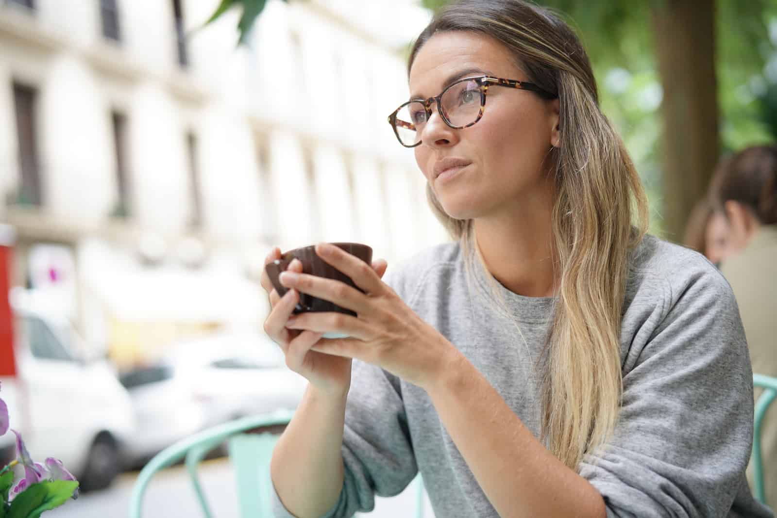 Femme prenant un café tout en regardant d'une manière pensive