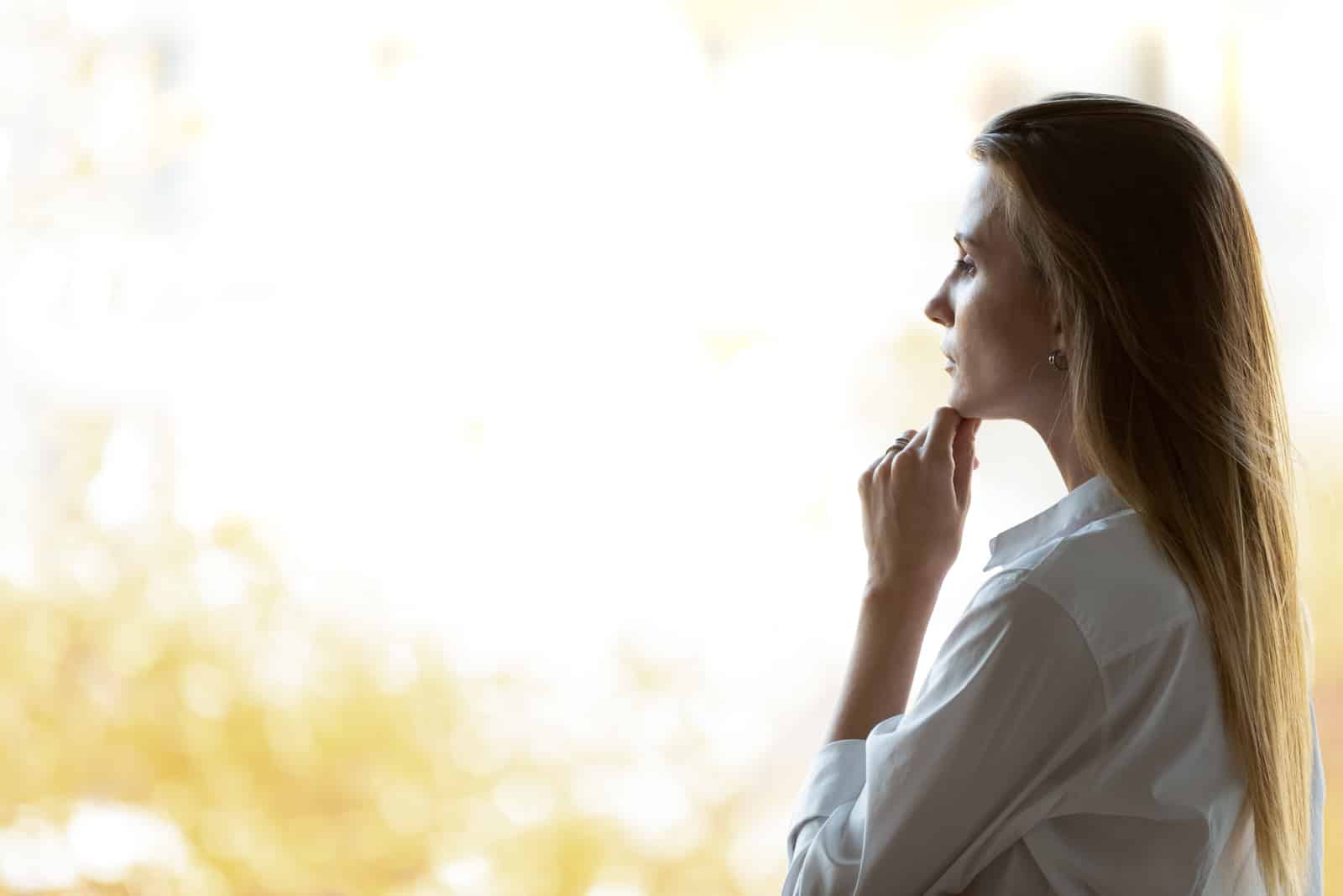 Femme regardant à travers la pensée de verre de fenêtre de bureau