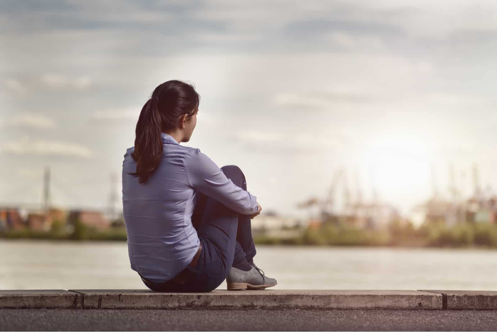 Femme regardant la rivière en position assise