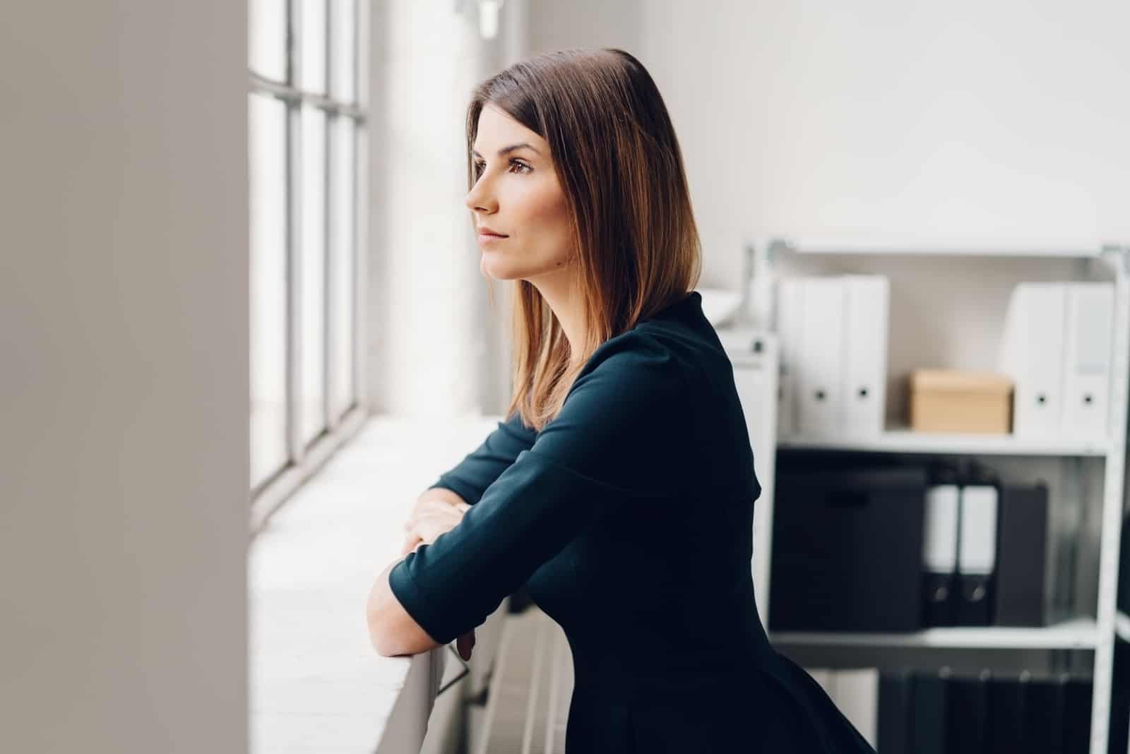 Jolie femme debout regardant par une fenêtre