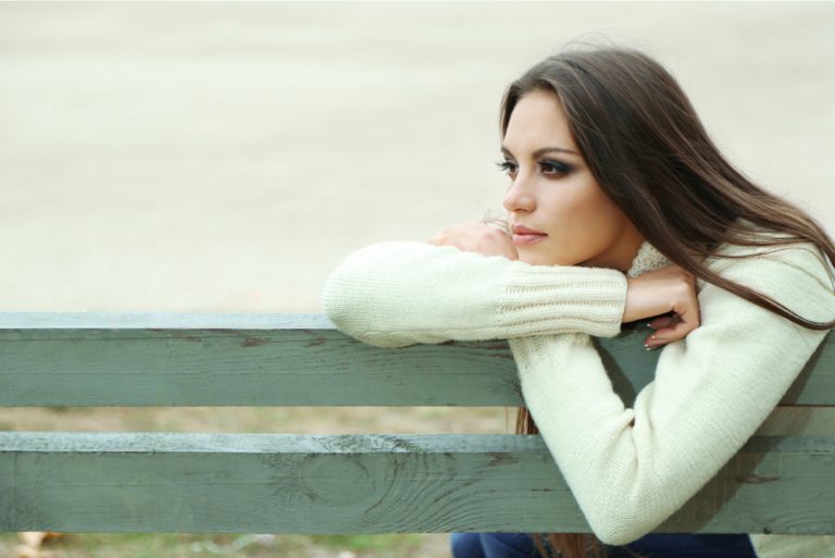 une femme triste assise sur un banc de parc